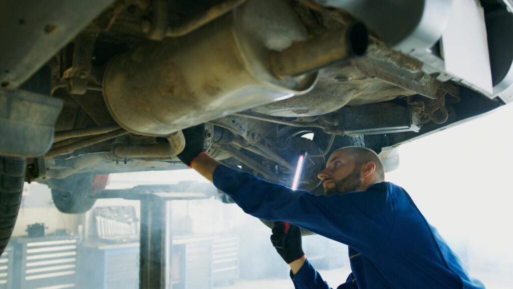 Mechanic inspecting vehicle suspension system in auto repair shop, highlighting car suspension service, maintenance, and repair in Canoga Park.