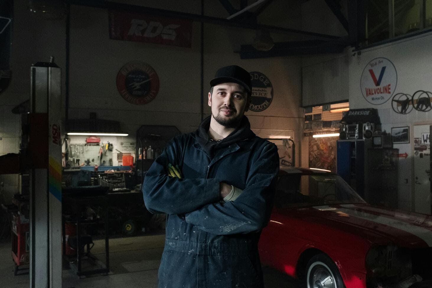 Mechanic in auto repair shop with tools and vintage car, representing vehicle maintenance and repair services in Canoga Park.