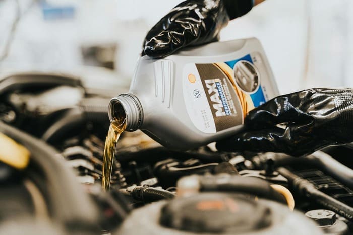 Person pouring motor oil into a car engine, highlighting car maintenance services at a full-service auto shop in Canoga Park, emphasizing quick oil change and vehicle repair services.
