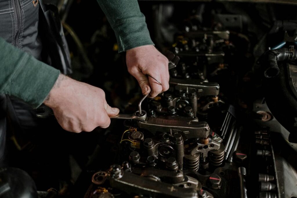 Mechanic working on engine components with a wrench, highlighting auto repair services in Canoga Park, including engine repair and maintenance.
