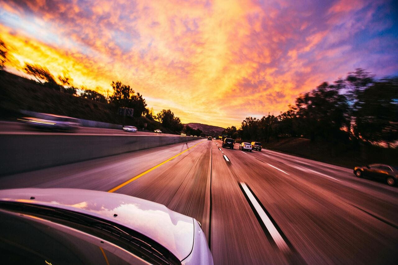 Cars driving on a highway at sunset, representing vehicle maintenance and auto repair services in Canoga Park, emphasizing quick oil change and transmission service options.
